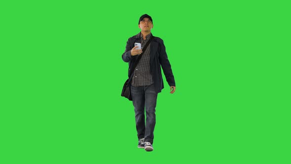 Hispanic Mailman Walking and Using His Phone Looking for the Right Address on a Green Screen Chroma