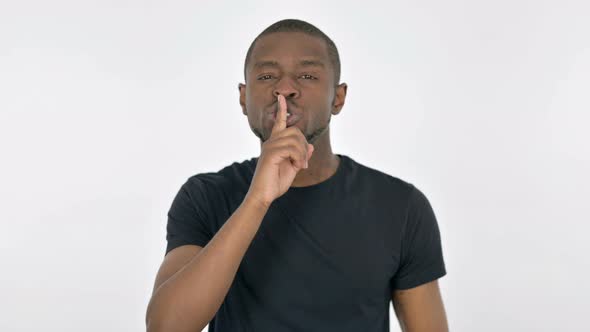 Silence Please Young African Man with Finger on Lips on White Background