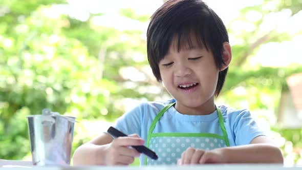 Cute Asian Child Drawing With Crayons On White Table