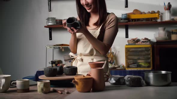 A female ceramicist is creating a new pottery in the workshop. Asian woman is enjoying pottery work.