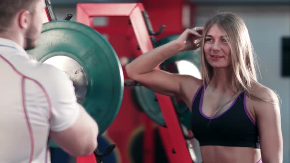 Athletic Man Showing His Biceps To Blonde Woman in Gym