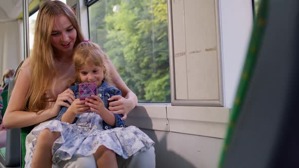 Mother with Daughter Traveling By Bus Going Home Playing on Smartphone Browsing Social Media