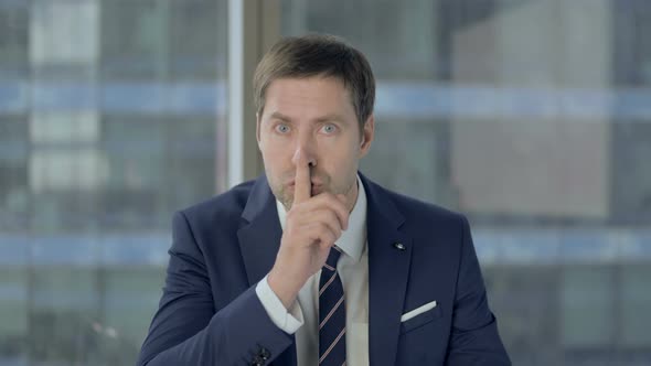 Happy Businessman Putting Finger on Lips