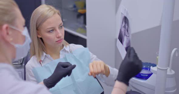 Beautiful Young Woman at the Consultation with the Dentist Watching an Xray with the Dentist