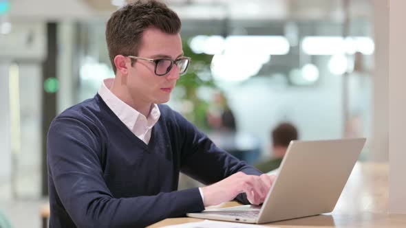 Young Businessman with Laptop Smiling at Camera 