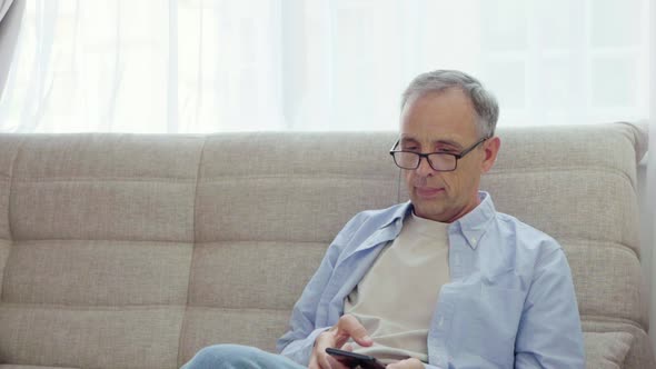 Elderly Man Rejoices Looking Into Smartphone