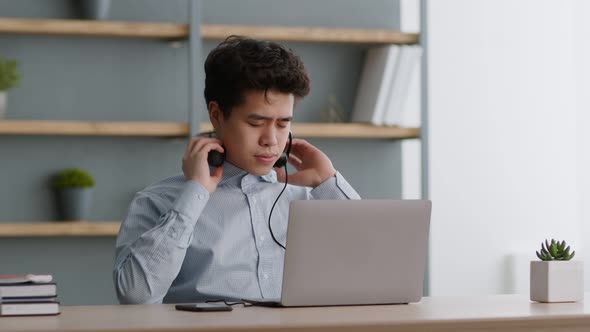 Young Asian Guy Taking Off Headset and Rubbing His Node Bridge Feeling Tired and Irritated of