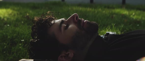 Man resting on his back on grass next to his camera