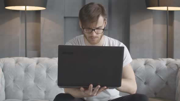 Front View Portrait of Concentrated Brunette Man Working Online with Laptop. Handsome Millennial