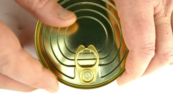 Hand Opens Metallic Tin Can of Canned Sardines or Mackerel in Vegetable Oil