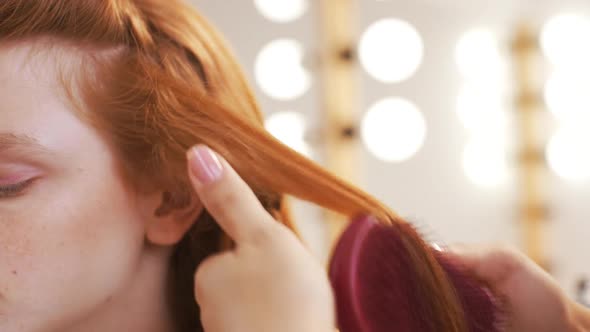 Female Hairdresser Combing Hair to Pretty Red Girl in Beauty Salon Slow Motion