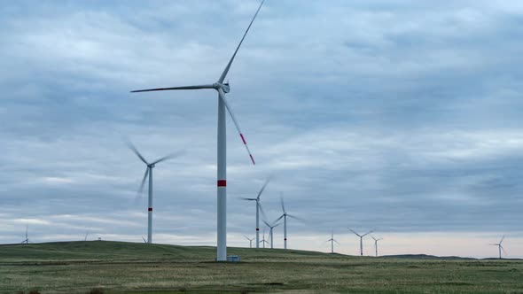 Blades of a Large Wind Turbine in a Field Against a Background of Cloudy Blue Sky on the Horizon