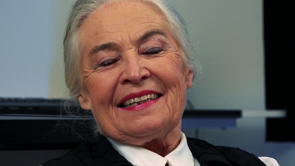 Old Caucasian Woman Smiles To Camera in Living Room - Closeup Face