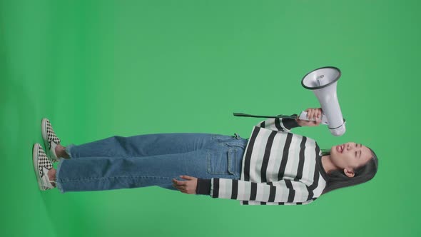 Full Body Side View Of An Asian Woman Shouting On Megaphone In The Green Screen Studio