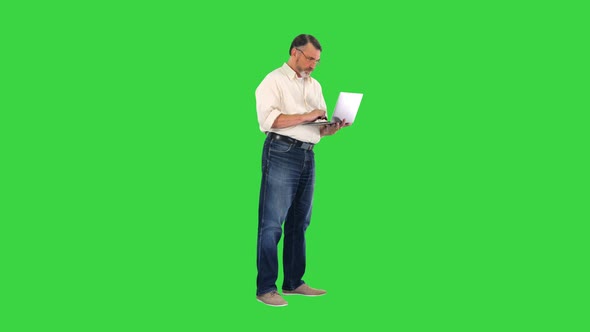 Upset Elderly Businessman Holding Laptop and Showing Disappointment on a Green Screen, Chroma Key.