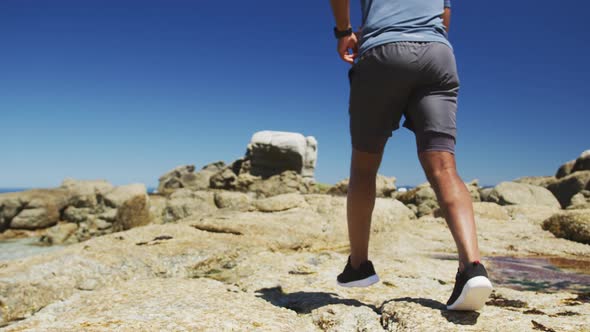 Senior african american man exercising running on rocks by the sea