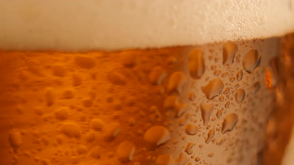 Detail Shot of Rotating Fresh Beer with Drops on Glass