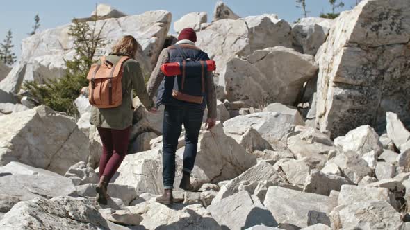 Couple Stepping Carefully on Rocks during Hiking Trip