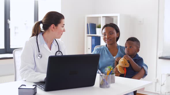 Mother with Baby and Doctor with Laptop at Clinic