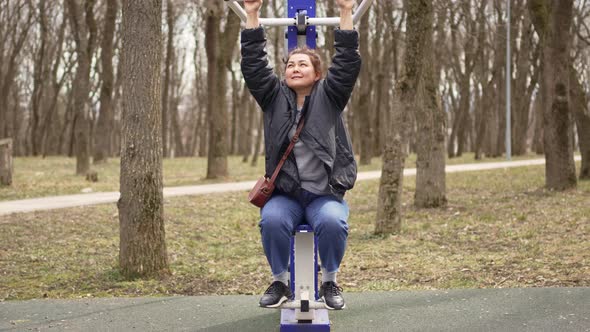 a Woman is Engaged in Mechanical Sports Simulators in the Park on a Walk