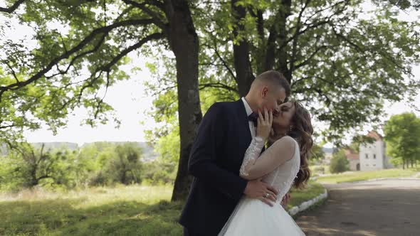 Caucasian Groom with Bride in the Park. Wedding Couple. Newlyweds Kissing