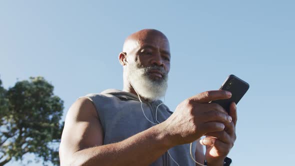 Senior african american man exercising using smartphone putting earphones in