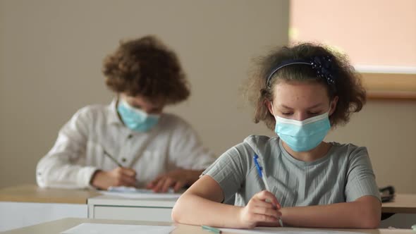 Reopen Schools. Schoolchildren in Masks. Back To School Covid. The Boy Passes the Note To the Girl