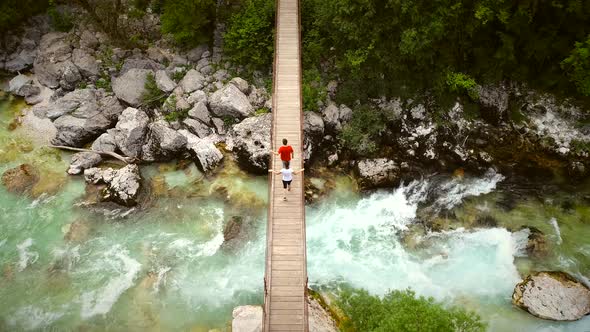 Aerial view of couple walking through a wooden bridge at the Soca River.