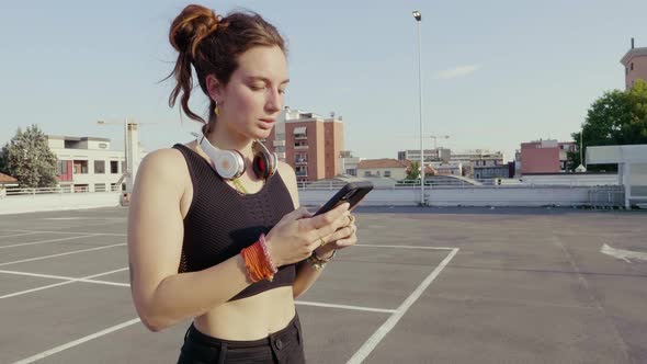 Slow motion shot of young woman using smartphone on parking deck