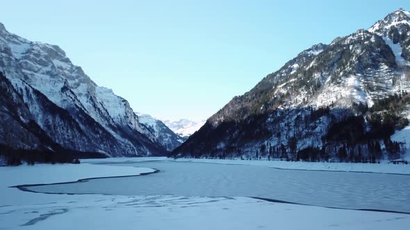 beautiful mountain range with a frozen lake in the middle, snowy forest and icy lake