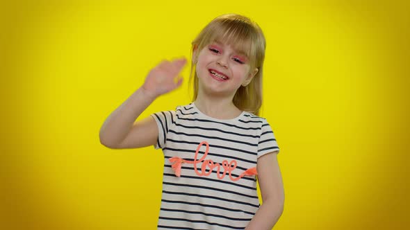 Little Blonde Child Kid Girl Waves Hand Palm in Hello Gesture Welcomes Someone Positive Emotions