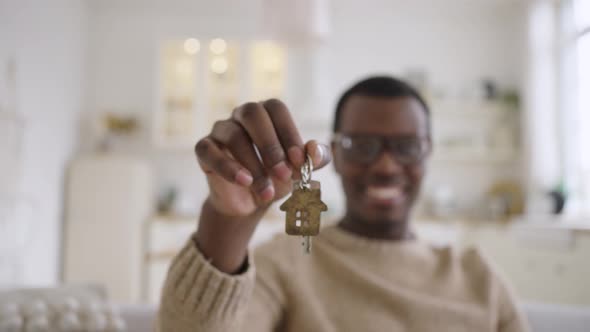 Happy Man Stretches Out Hand Showing Key to New Apartment