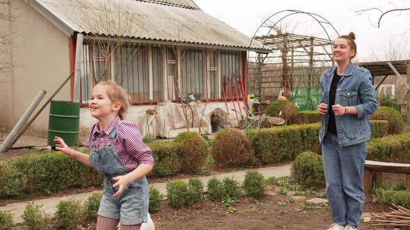 Two Girls Play Ball with Dog on a Farm or in a Village Yard