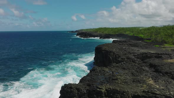 Aerial Top View of Waves Break on Rocks in a Blue Ocean