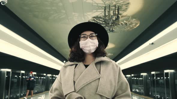 Portrait of an Attractive Young Woman in a Protective Medical Suit Standing Alone at an Empty Metro