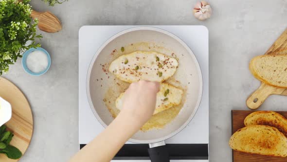 Crop person seasoning chicken fillet during dinner preparation