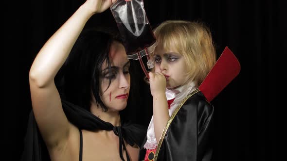 Woman and Child Dracula. Halloween Vampire Make-up. Kid with Blood on Her Face