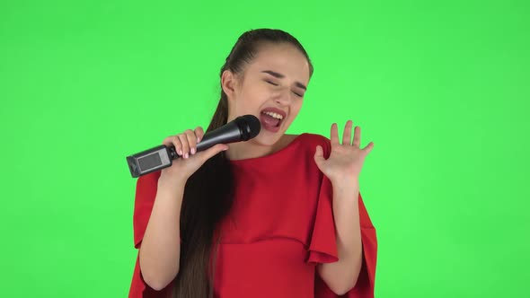 Portrait of Pretty Young Woman Is Singing Into a Microphone and Moving To the Beat of Music. Green