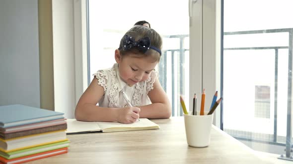 Little Schoolgirl Is Doing Her Homework. Cute Child Learns Lessons on His Own. Back To School.