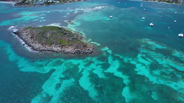 Aerial over shallow clear blue waters from Pinel Island to St. Martin (French Caribbean) on a bright