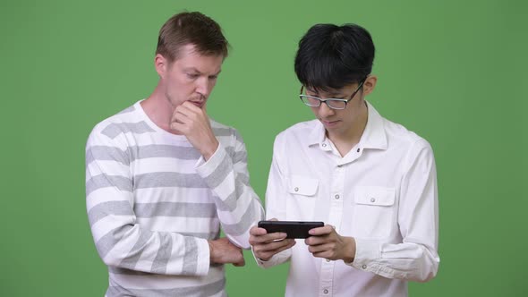 Two Young Multi-ethnic Businessmen Using Phone Together