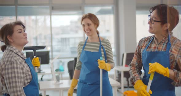 Cleaners Team in Uniform Bumping Fists Working Together in Modern Coworking Center Office