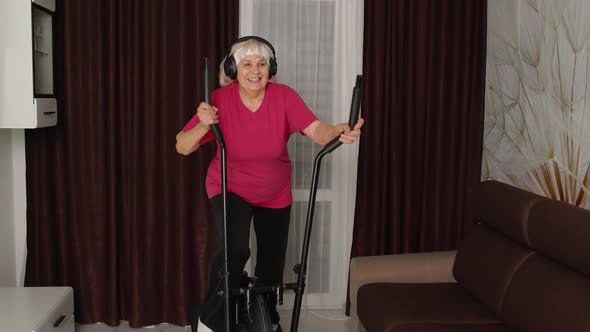 Senior Woman in Sportswear Using Orbitrek Listening Music at Home Doing Sport Cardio Exercises