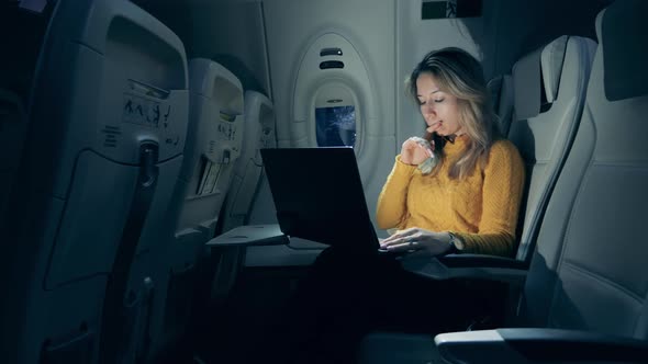 Airplane at Night with a Young Woman Operating a Laptop