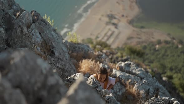 Slow Motion Young Woman Hiker Rock Climber Climbs Up on Cliff on Mountain Over Beautiful Sea Coast