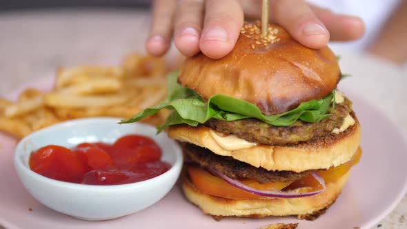 A Hand Fixing a Bun of the Plant Based Double Decker Burger