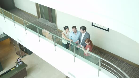 Business professionals meeting in corridor overlooking building atrium