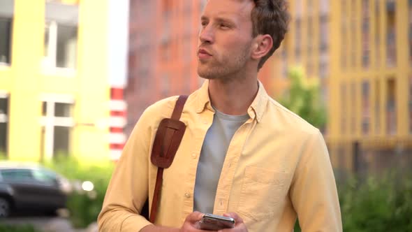 Positive guy standing in the middle of the street is using the phone.