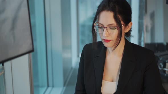Closeup Portrait of a Young Woman in a Business Suit at Workplace. Business Woman Working on