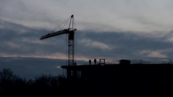 Silhouettes of workers on the top of residental building.